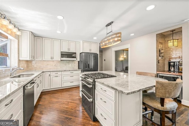 kitchen featuring appliances with stainless steel finishes, sink, a center island, dark hardwood / wood-style flooring, and a breakfast bar area