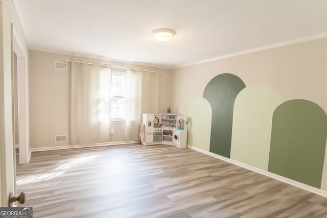 spare room featuring crown molding and light hardwood / wood-style floors