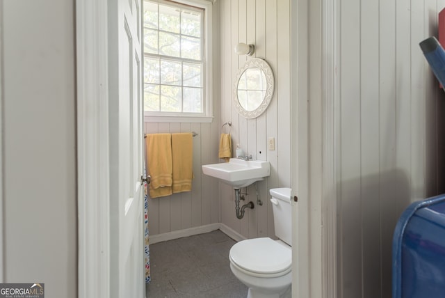 bathroom featuring wood walls and toilet