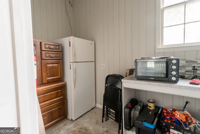 kitchen with white refrigerator and wooden walls