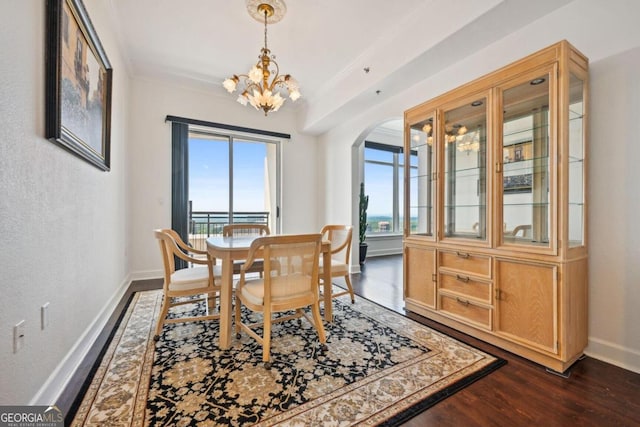 dining area with arched walkways, baseboards, ornamental molding, dark wood-style floors, and an inviting chandelier