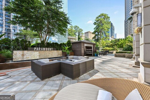 view of patio with a view of city, outdoor dining area, an outdoor living space with a fire pit, and an outbuilding