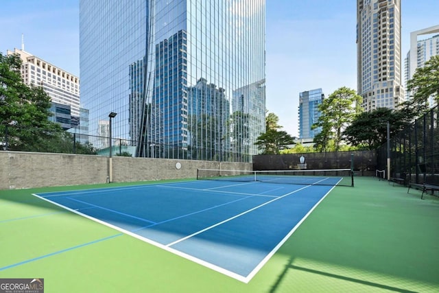 view of tennis court with fence and a city view