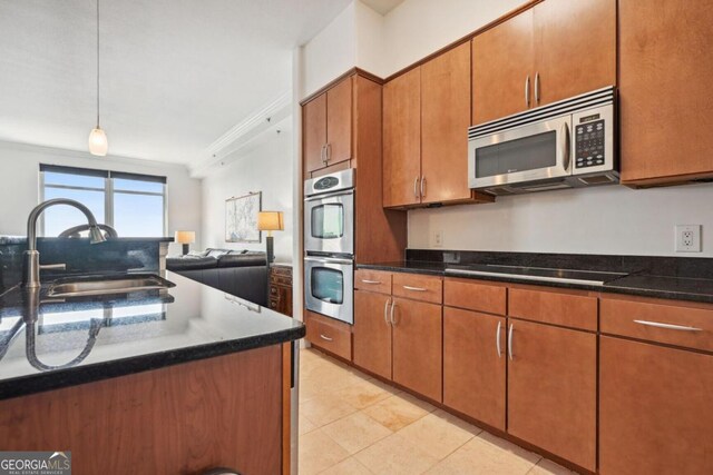 kitchen featuring crown molding, appliances with stainless steel finishes, brown cabinetry, open floor plan, and a sink