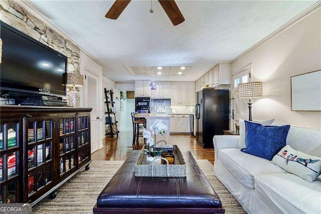 living room with ceiling fan, ornamental molding, a textured ceiling, and light hardwood / wood-style floors