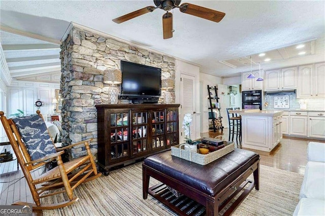 living room with a textured ceiling, crown molding, and ceiling fan