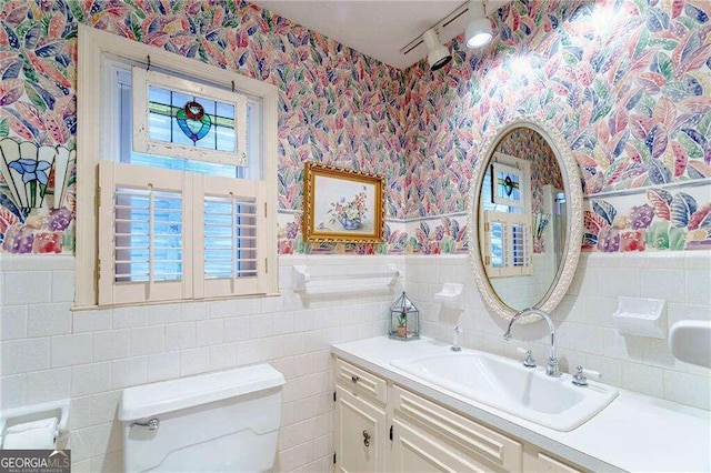 bathroom with tile walls, vanity, and toilet