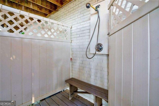 bathroom with wooden walls, wood-type flooring, and brick wall