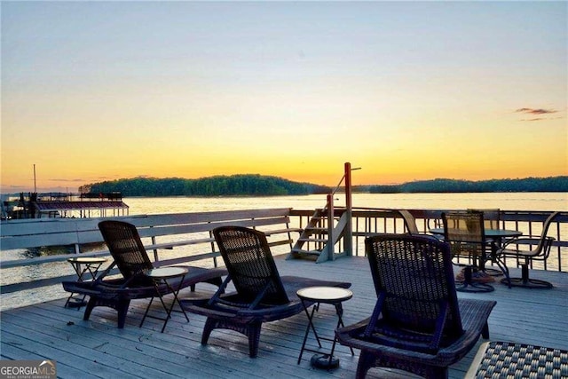 deck at dusk featuring a water view