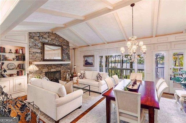 living room featuring french doors, lofted ceiling with beams, a fireplace, a notable chandelier, and light wood-type flooring