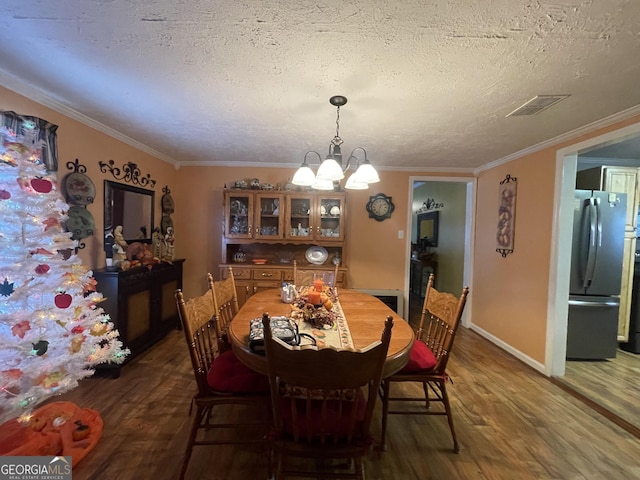 dining space with crown molding, dark wood-type flooring, a textured ceiling, and an inviting chandelier