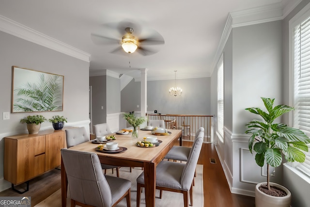 dining area featuring crown molding, dark wood-type flooring, and ceiling fan with notable chandelier