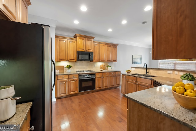 kitchen with sink, crown molding, light hardwood / wood-style flooring, tasteful backsplash, and black appliances