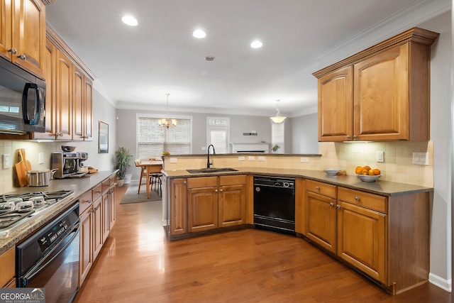 kitchen featuring pendant lighting, kitchen peninsula, sink, and black appliances