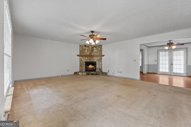 unfurnished living room featuring ceiling fan, a textured ceiling, a fireplace, and light carpet