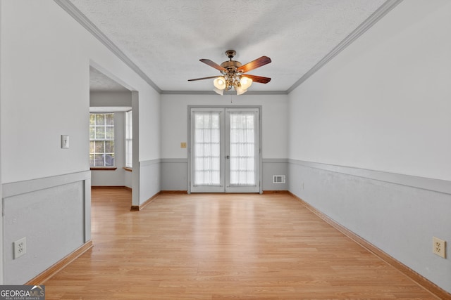 spare room featuring a wealth of natural light, ceiling fan, light wood-type flooring, and a textured ceiling