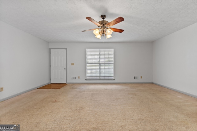 empty room with a textured ceiling, ceiling fan, and light colored carpet