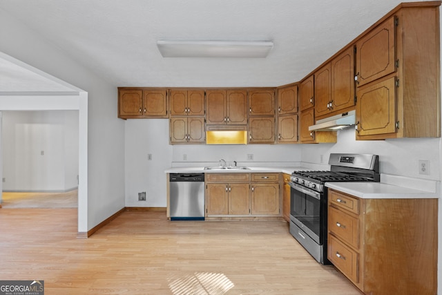 kitchen with a textured ceiling, light hardwood / wood-style floors, sink, and stainless steel appliances