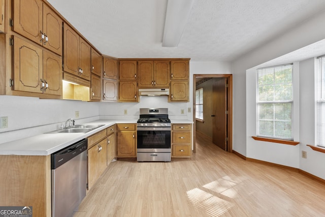 kitchen with a textured ceiling, stainless steel appliances, sink, and light hardwood / wood-style floors