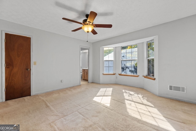 empty room featuring light carpet, ceiling fan, and a textured ceiling