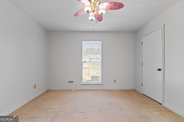 unfurnished room with ceiling fan, light colored carpet, and a textured ceiling