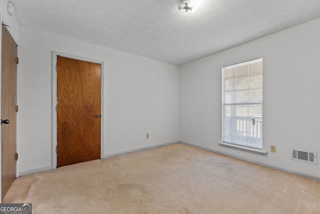 carpeted empty room featuring a textured ceiling