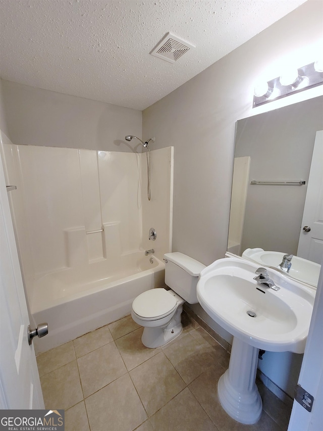 bathroom with a textured ceiling, tile patterned flooring, toilet, and  shower combination