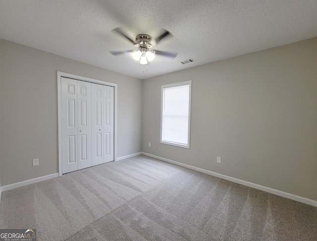 unfurnished bedroom with ceiling fan, a textured ceiling, a closet, and carpet flooring