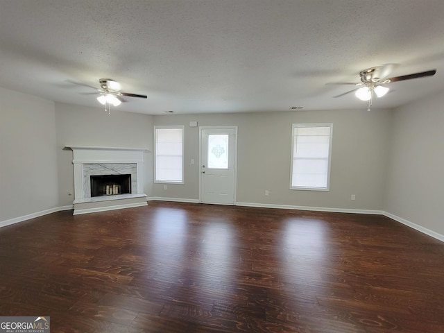 unfurnished living room featuring a high end fireplace, dark wood-type flooring, and ceiling fan