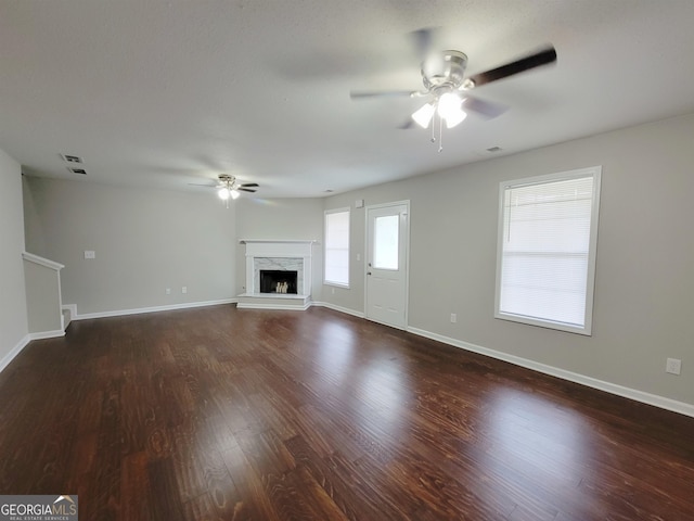 unfurnished living room with a fireplace, dark wood-type flooring, and ceiling fan