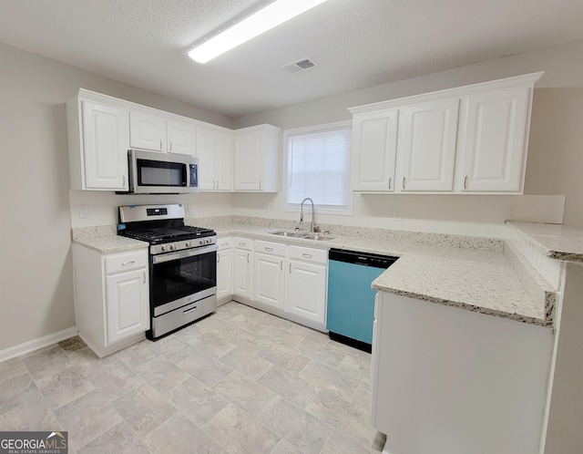 kitchen with a textured ceiling, sink, white cabinets, appliances with stainless steel finishes, and light stone countertops