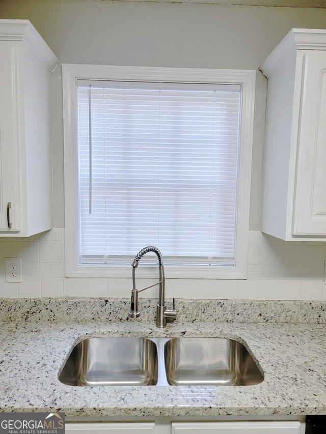 kitchen with tasteful backsplash, sink, light stone counters, and white cabinets