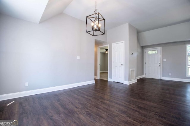 unfurnished dining area featuring ceiling fan with notable chandelier, dark hardwood / wood-style floors, and vaulted ceiling