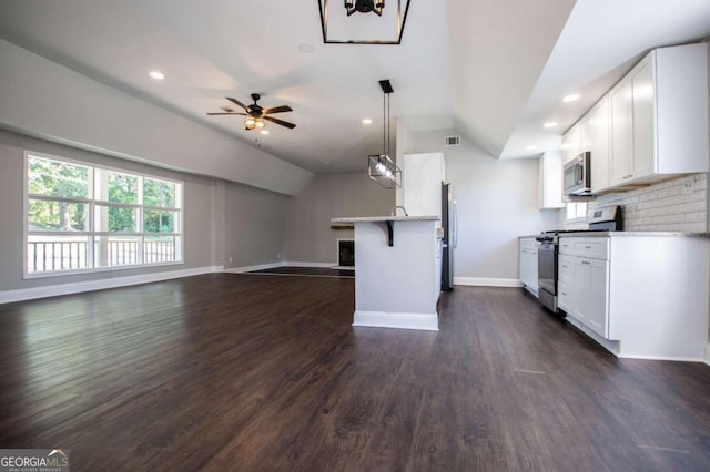 kitchen featuring white cabinets, appliances with stainless steel finishes, dark wood-type flooring, and lofted ceiling