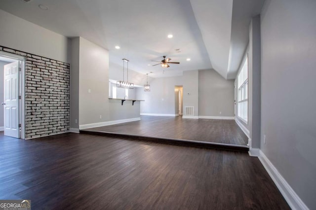 unfurnished living room featuring ceiling fan with notable chandelier, dark hardwood / wood-style flooring, and lofted ceiling