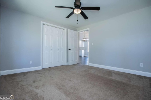 unfurnished bedroom featuring carpet floors, ceiling fan with notable chandelier, and a closet