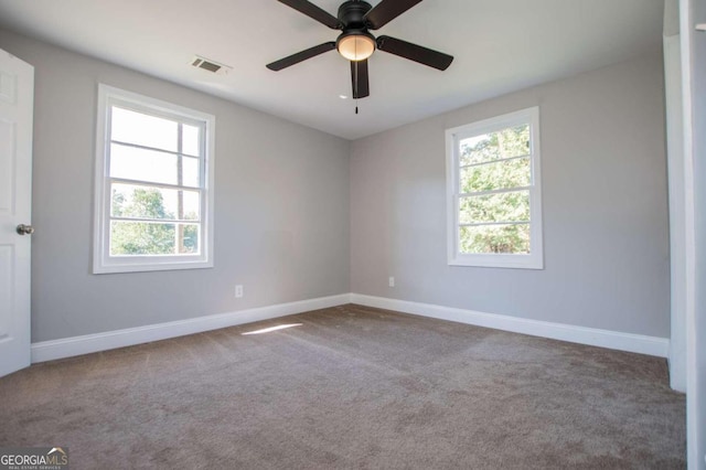 carpeted spare room with ceiling fan and plenty of natural light