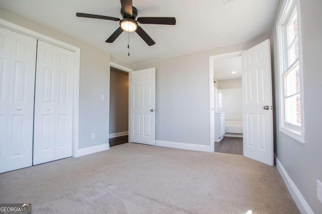 unfurnished bedroom featuring ensuite bath, ceiling fan, light colored carpet, and a closet