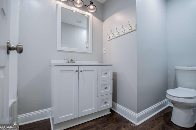 bathroom with wood-type flooring, vanity, and toilet