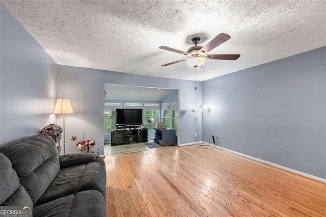 living room with ceiling fan, wood-type flooring, and a textured ceiling