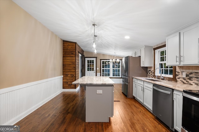 kitchen with appliances with stainless steel finishes, dark wood-type flooring, pendant lighting, a center island, and sink