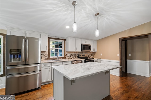 kitchen with stainless steel appliances, white cabinets, decorative light fixtures, and sink