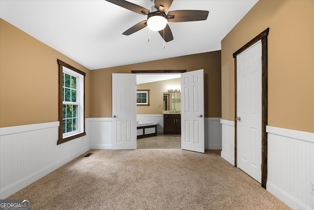 unfurnished bedroom with ceiling fan, light colored carpet, and vaulted ceiling