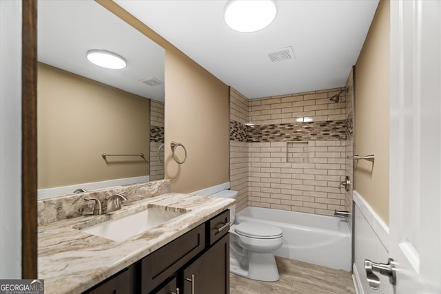 full bathroom featuring wood-type flooring, tiled shower / bath combo, vanity, and toilet