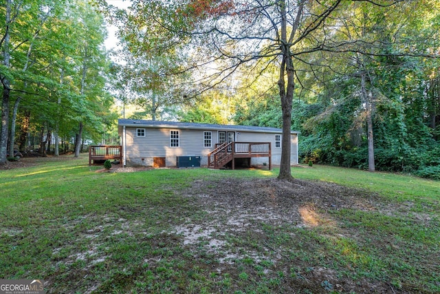 back of house with a deck, a lawn, and central AC