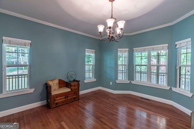 spare room featuring ornamental molding, a notable chandelier, plenty of natural light, and dark hardwood / wood-style floors