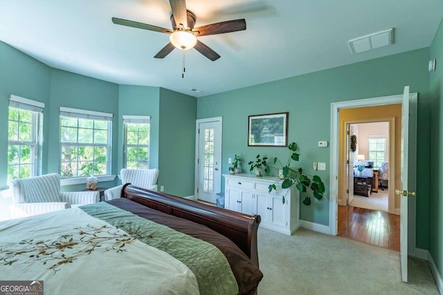 bedroom with ceiling fan, light colored carpet, and multiple windows