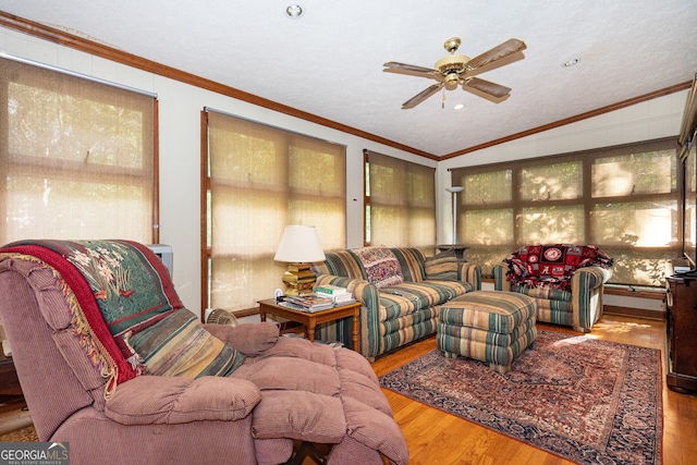 living room with lofted ceiling, ornamental molding, hardwood / wood-style floors, and ceiling fan