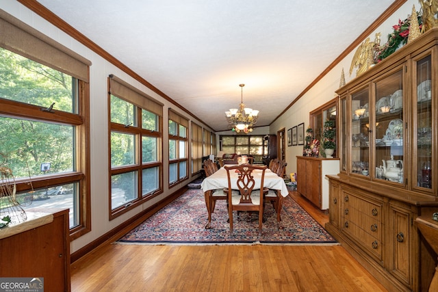 dining area with crown molding, an inviting chandelier, and light hardwood / wood-style flooring