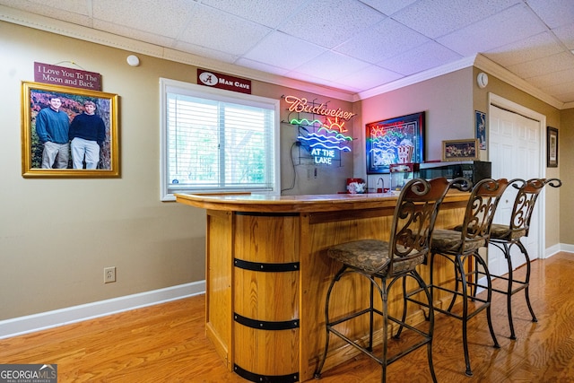 bar with wood-type flooring, a paneled ceiling, and crown molding